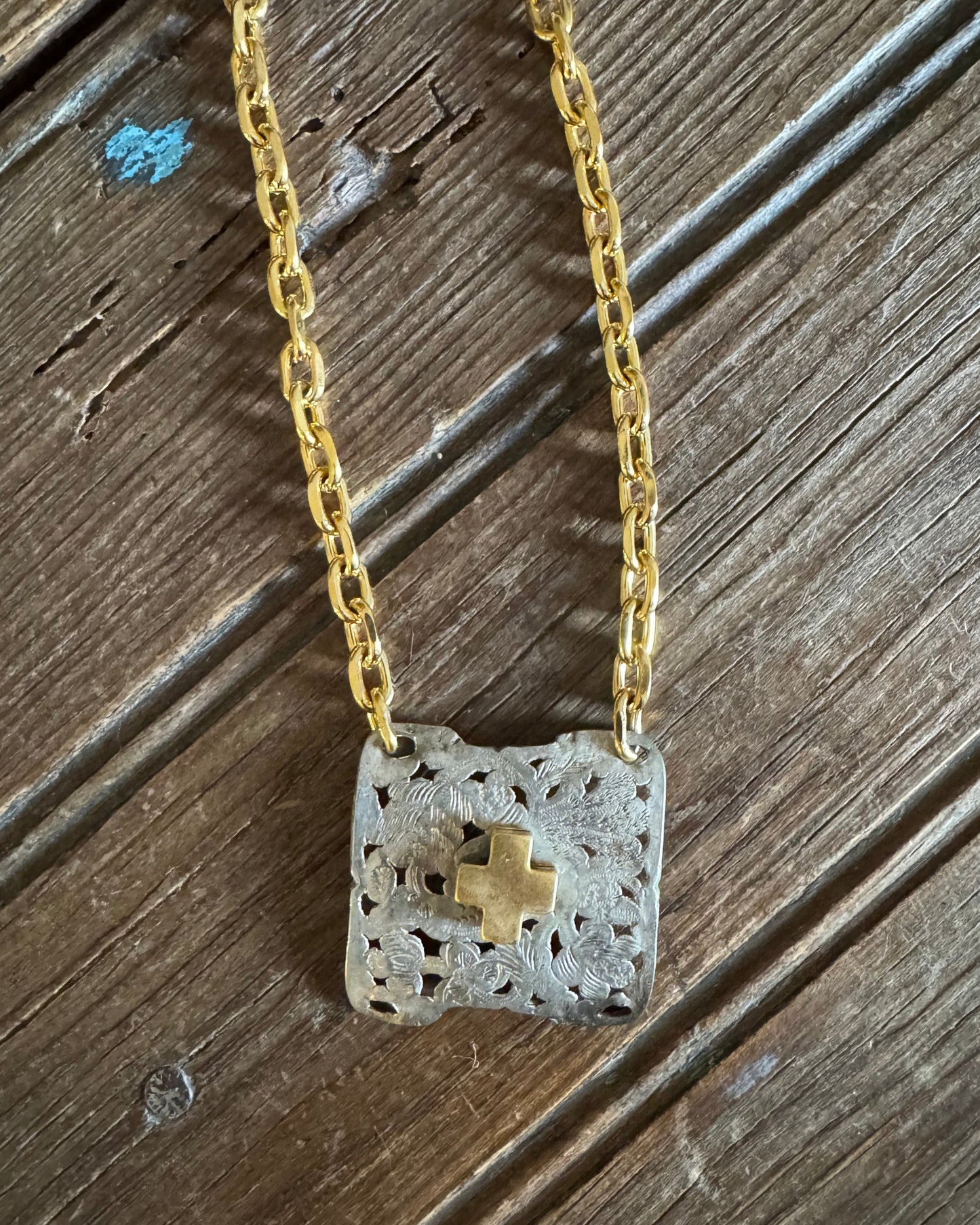 gold and silver buckle necklace on a rustic wood background