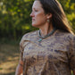 Woman wearing a patterned shirt with a blurred green background