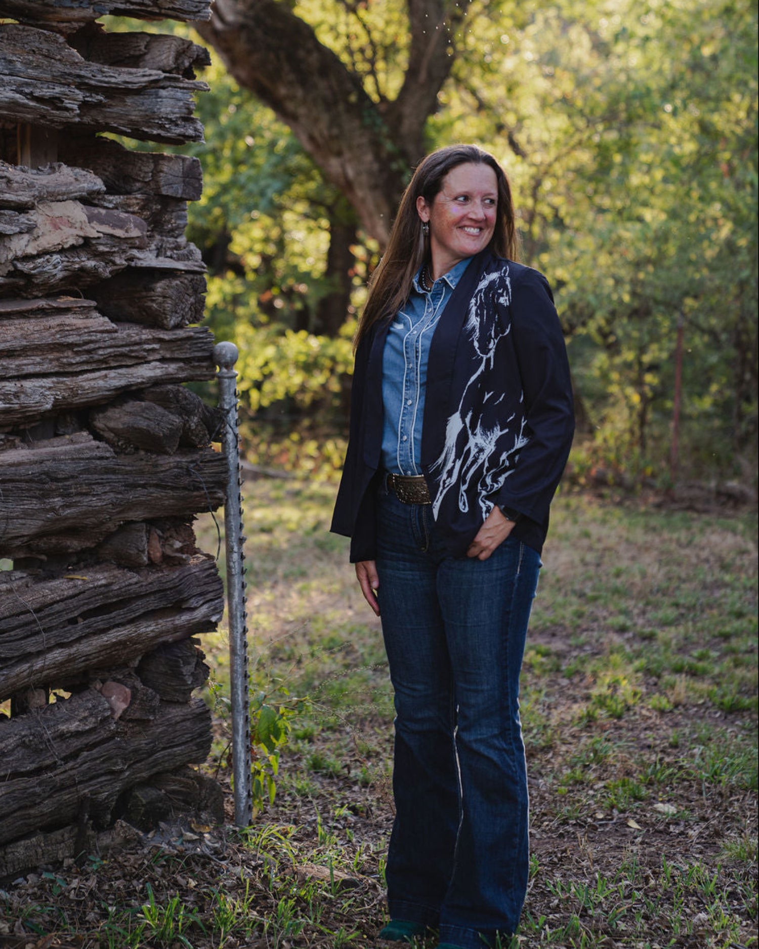 Woman standing in front of a rustic wooden cabin in a forest setting