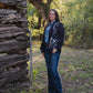 Woman standing in front of a rustic wooden cabin in a forest setting