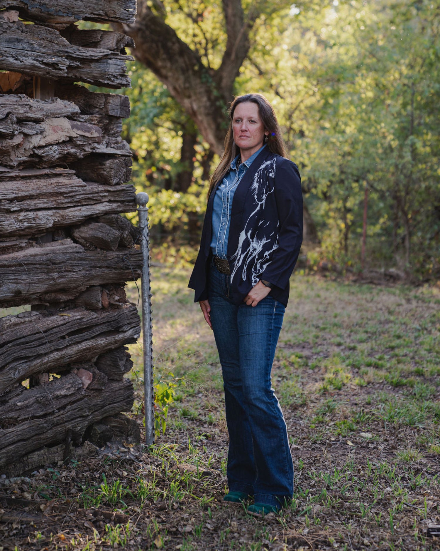 Woman standing in front of a rustic wooden cabin in a forest setting