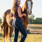 Woman standing next to a horse in an outdoor setting