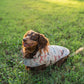 Dog wearing a patterned coat sitting on grass