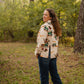 model wearing a coat and jeans standing in the woods 