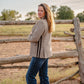 Woman standing by a wooden fence in a rural setting