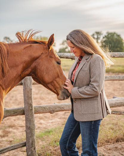 Woman standing next to a horse near a wooden fence with a natural background