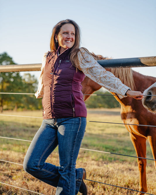 Woman standing next to a horse in an outdoor setting