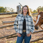 Woman standing next to a horse near a wooden fence in a rural setting