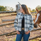 Woman standing next to a horse near a wooden fence in a rural setting