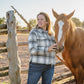Woman standing next to a horse near a wooden fence