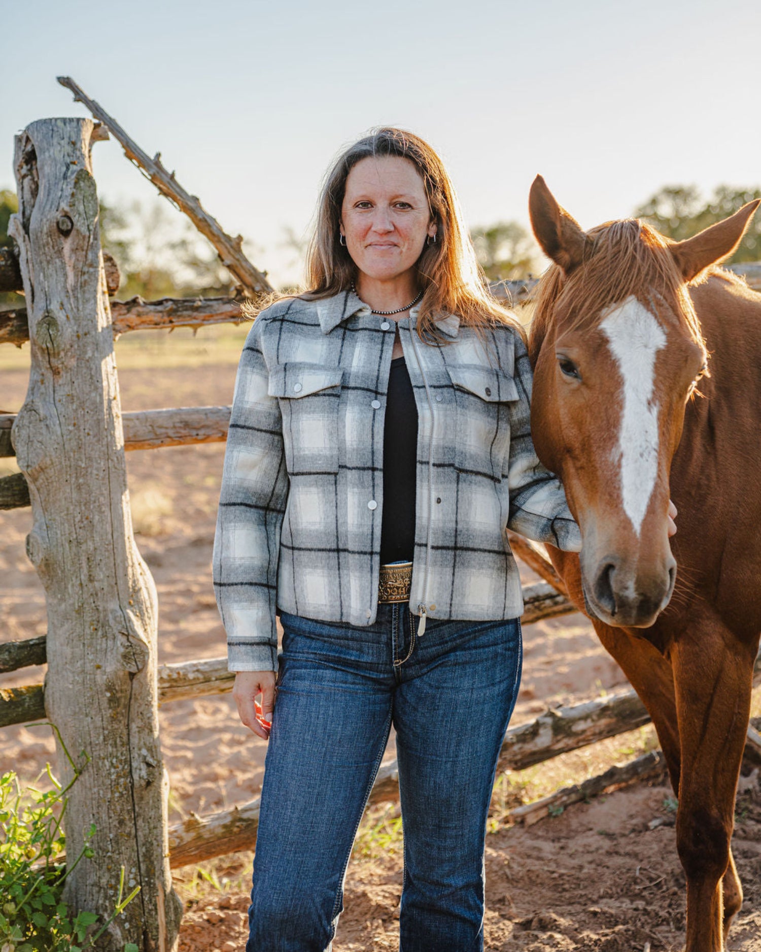 Woman standing next to a horse in a rural setting