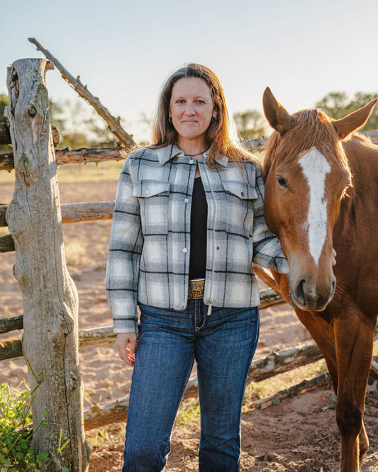 Woman standing next to a horse in a rural setting