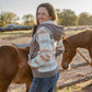 Woman standing with two horses in a rural setting