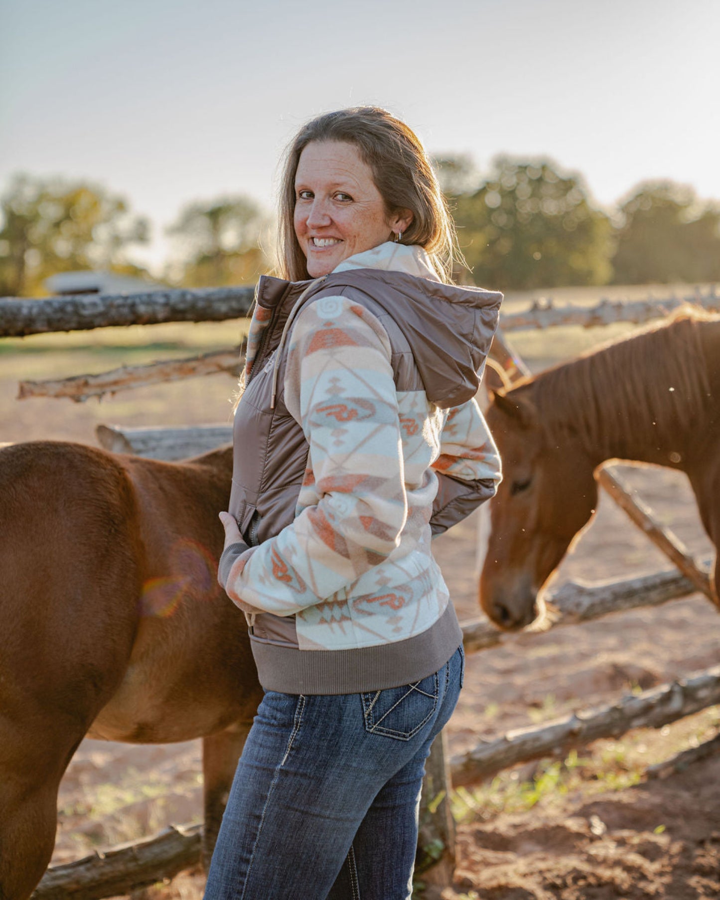 Woman standing with two horses in a rural setting