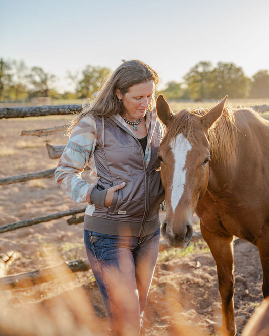 Woman standing next to a horse in an outdoor setting