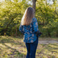 Person wearing a blue floral shirt standing in a forested area