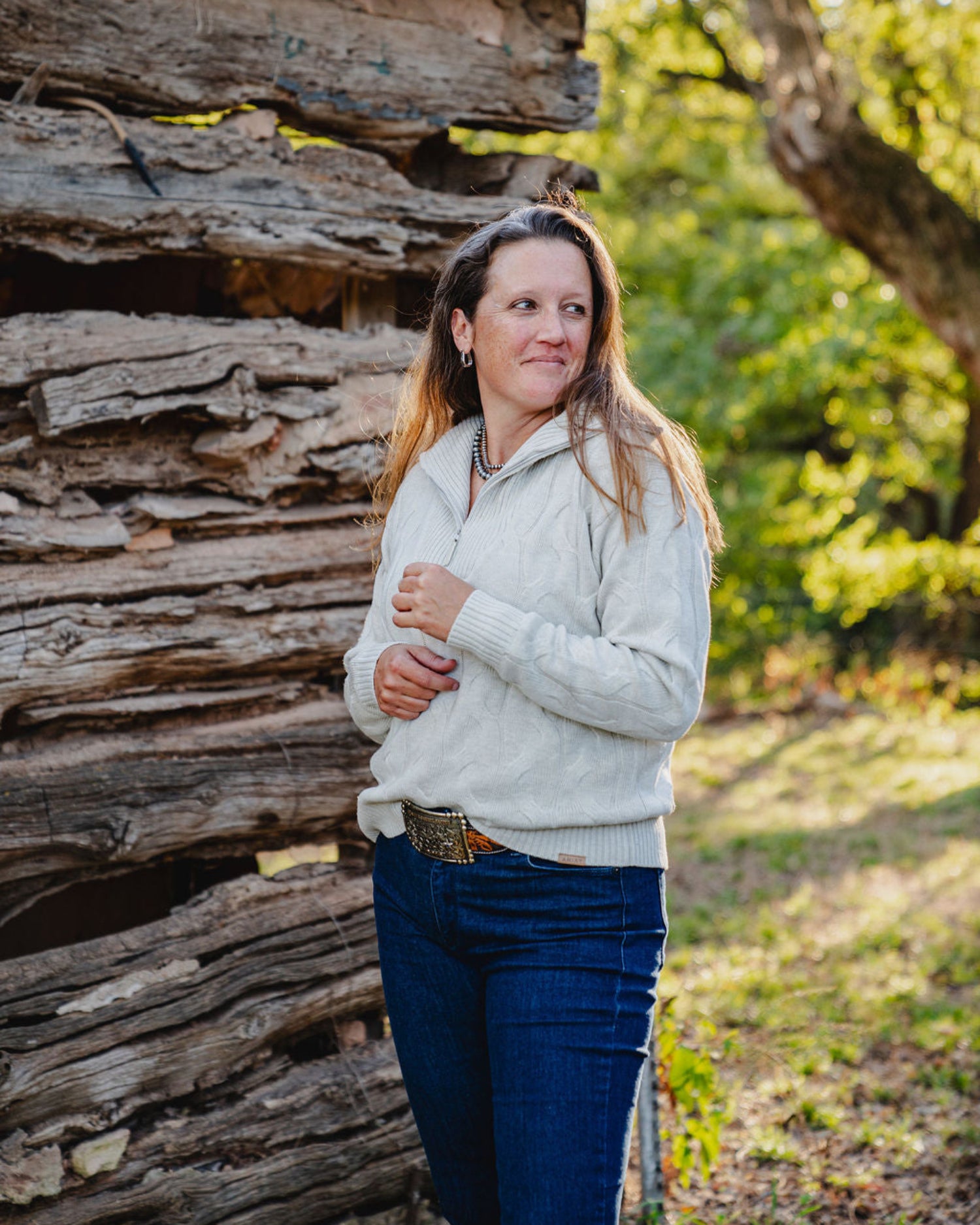 Woman standing in front of a wooden structure with trees in the background
