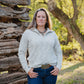 Woman standing in a natural setting with trees and wooden logs.