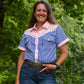 Woman wearing a blue checkered shirt with pink accents outdoors