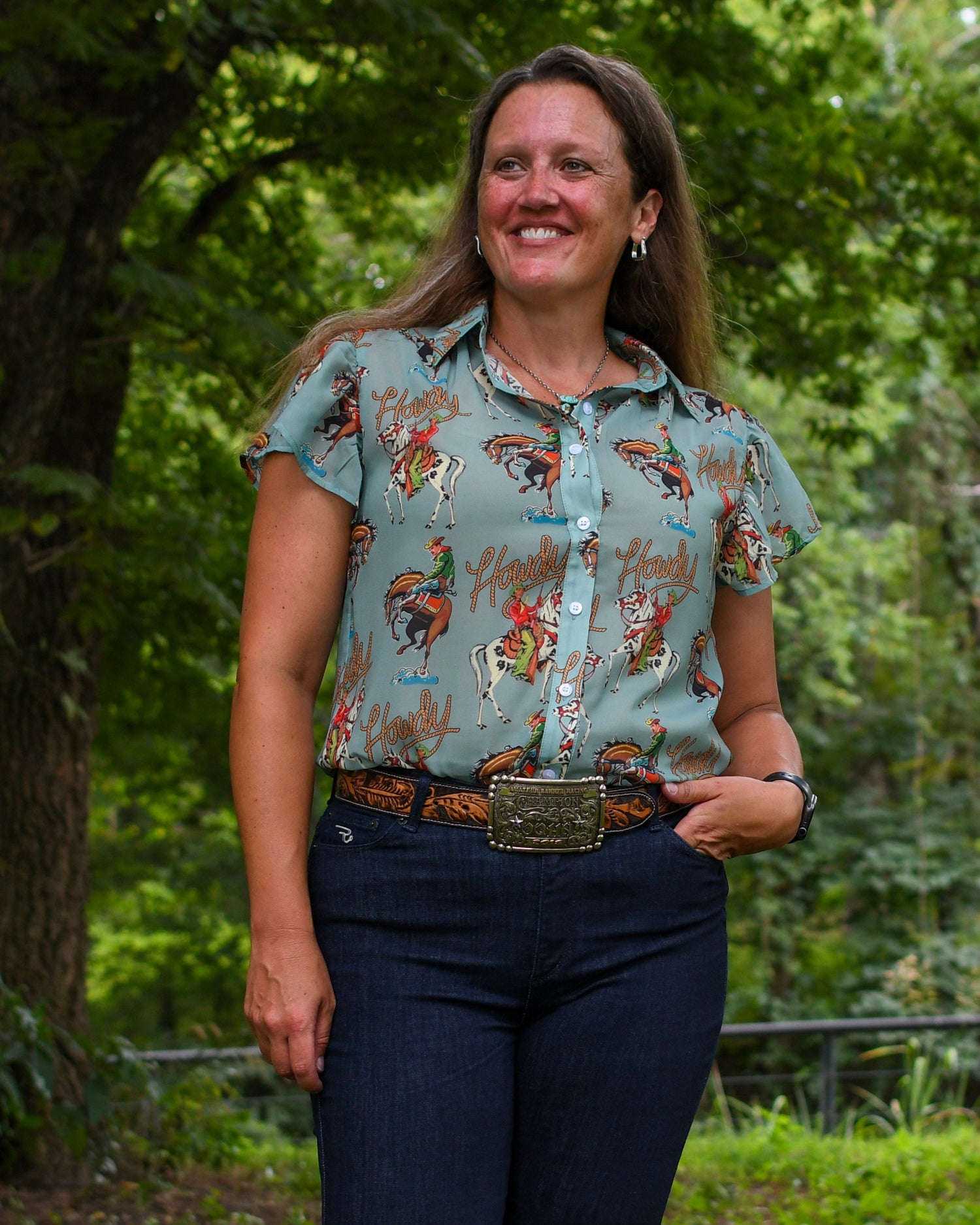 Woman wearing a patterned shirt and jeans standing in a forested area