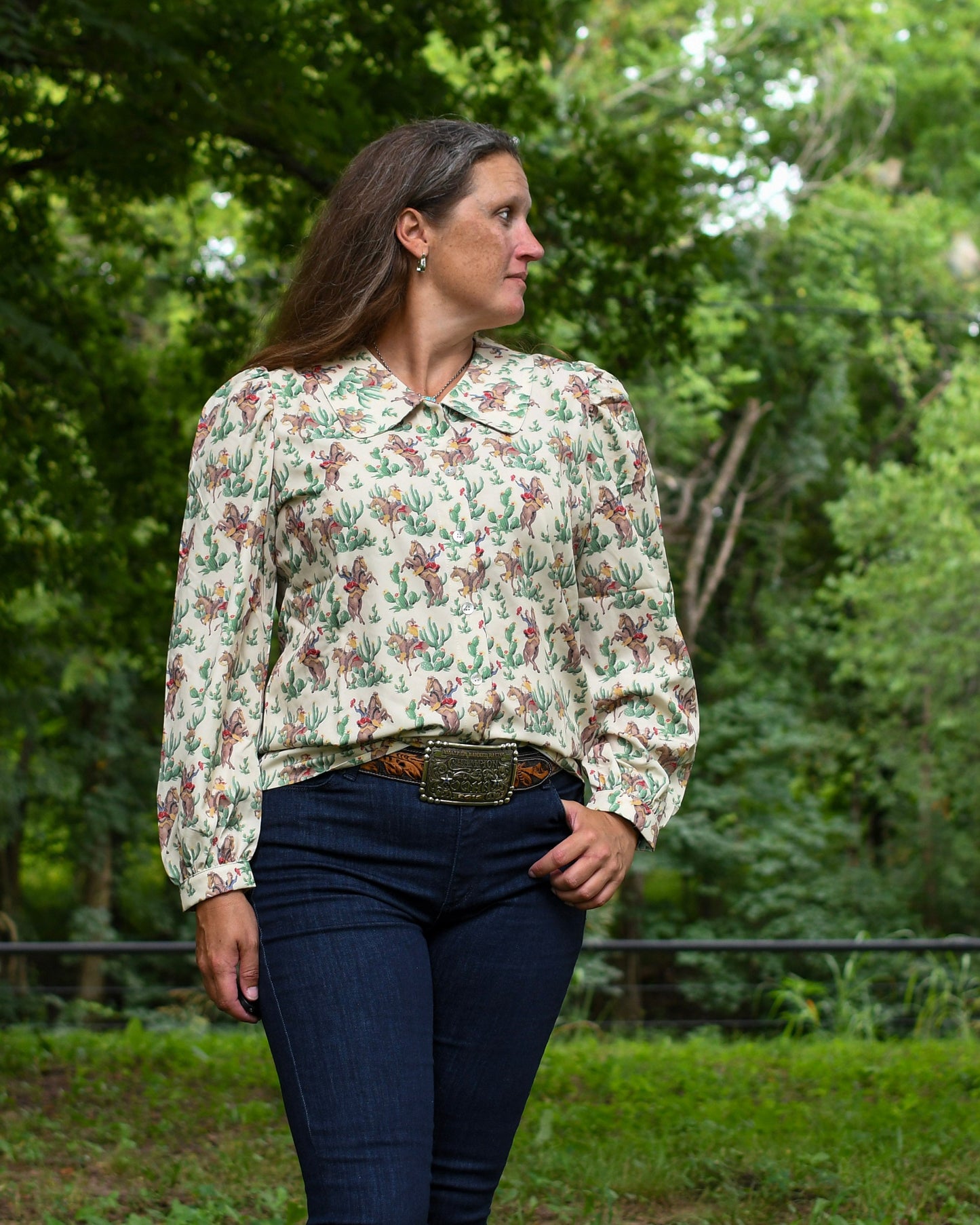 Woman wearing a floral blouse and jeans standing in a forested area
