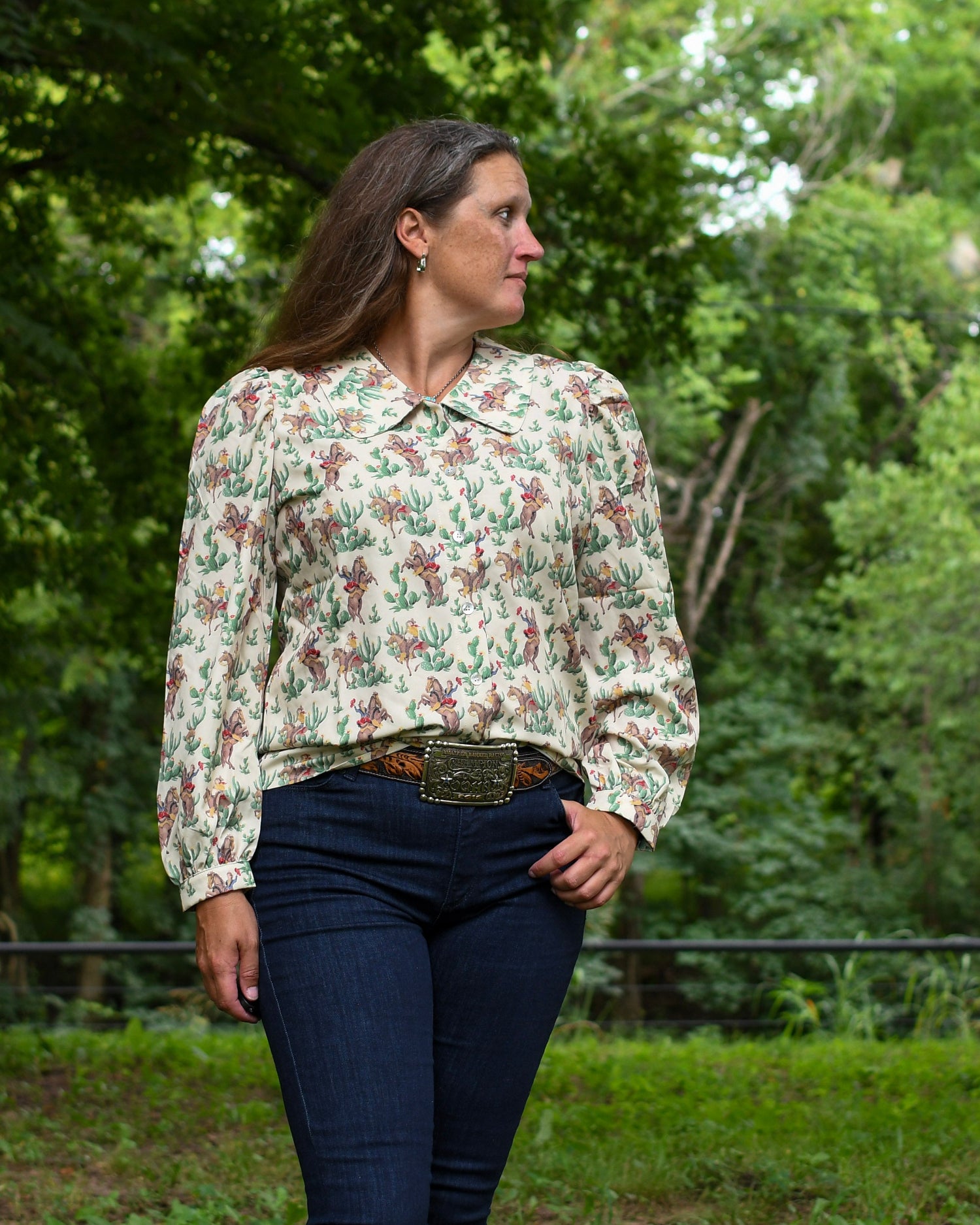 Woman wearing a floral blouse and jeans standing in a forested area