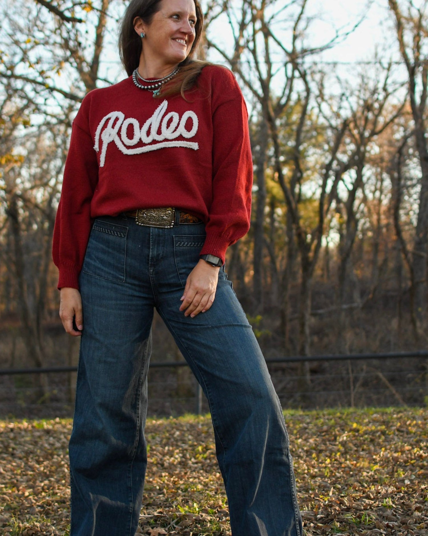 Model in sweater and jeans standing in trees