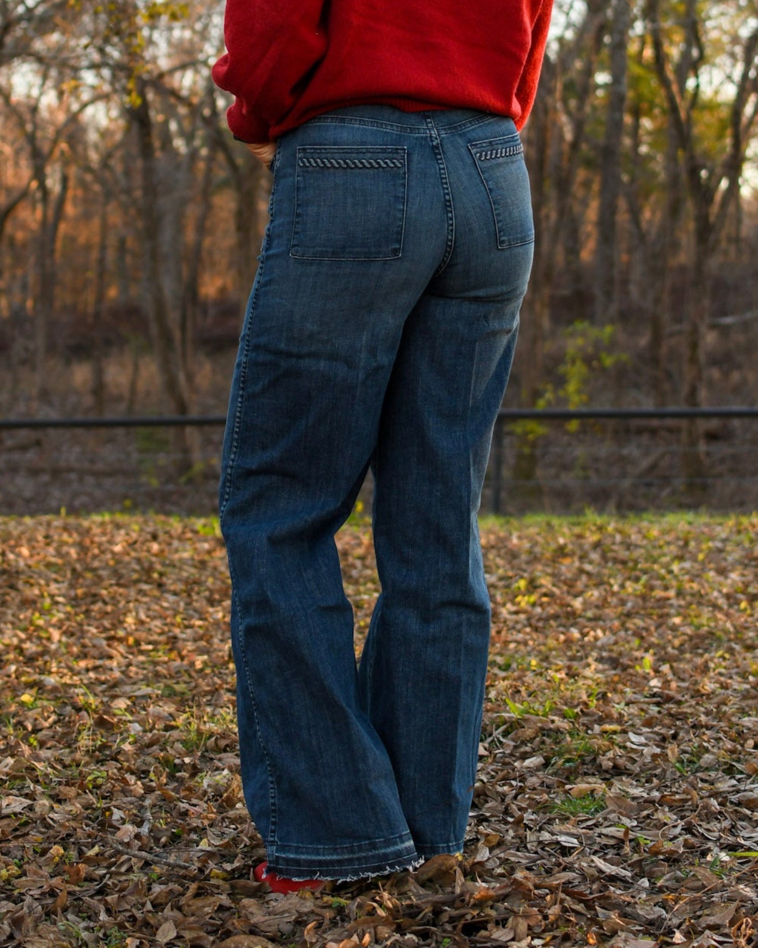 model standing in leaves wearing jeans and a sweater