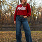 Model standing in leaves wearing a rodeo sweater and jeans