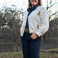 woman in trees wearing a cardigan sweater and jeans 