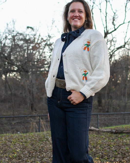 woman in trees wearing a cardigan sweater and jeans 