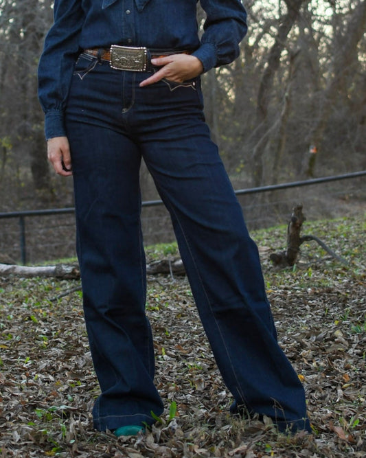 Model wearing a denim outfit with a background of trees 