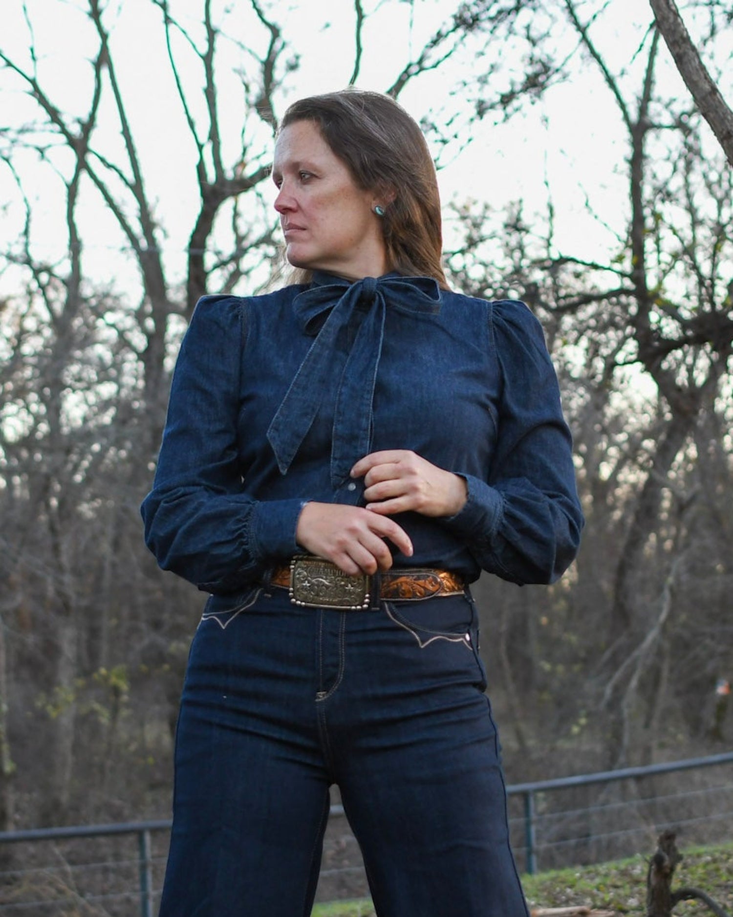 woman wearing all denim standing by a tree