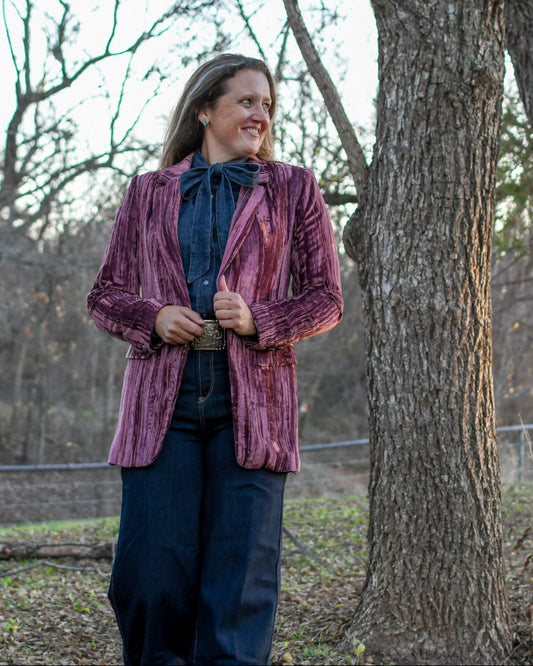 Model standing in trees wearing a blazer and jeans