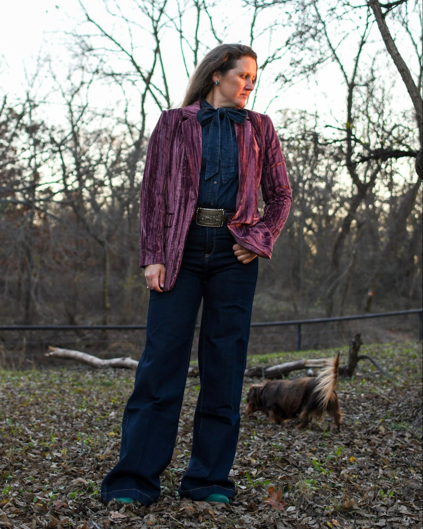 Woman standing outside wearing a blazer and jeans with a dog