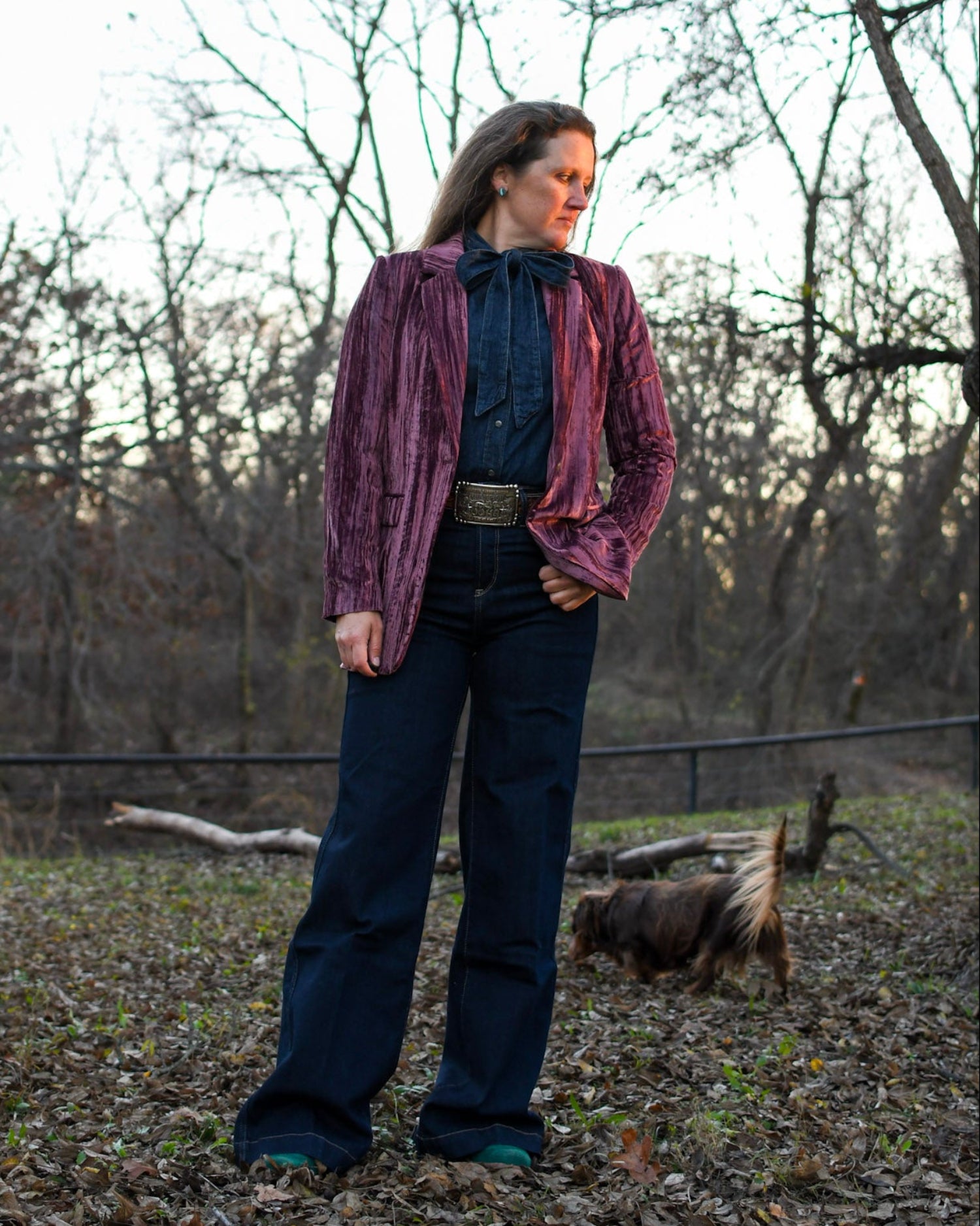 Woman standing outside wearing a blazer and jeans with a dog