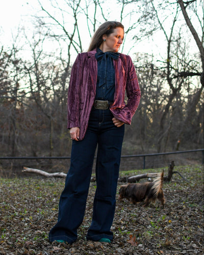 Woman standing outside wearing a blazer and jeans with a dog