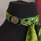 Green patterned scarf tied around a black mannequin head with a blurred background