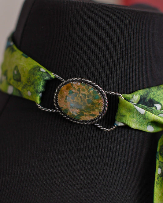 mannequin with a green patterned band and decorative button on a neutral background