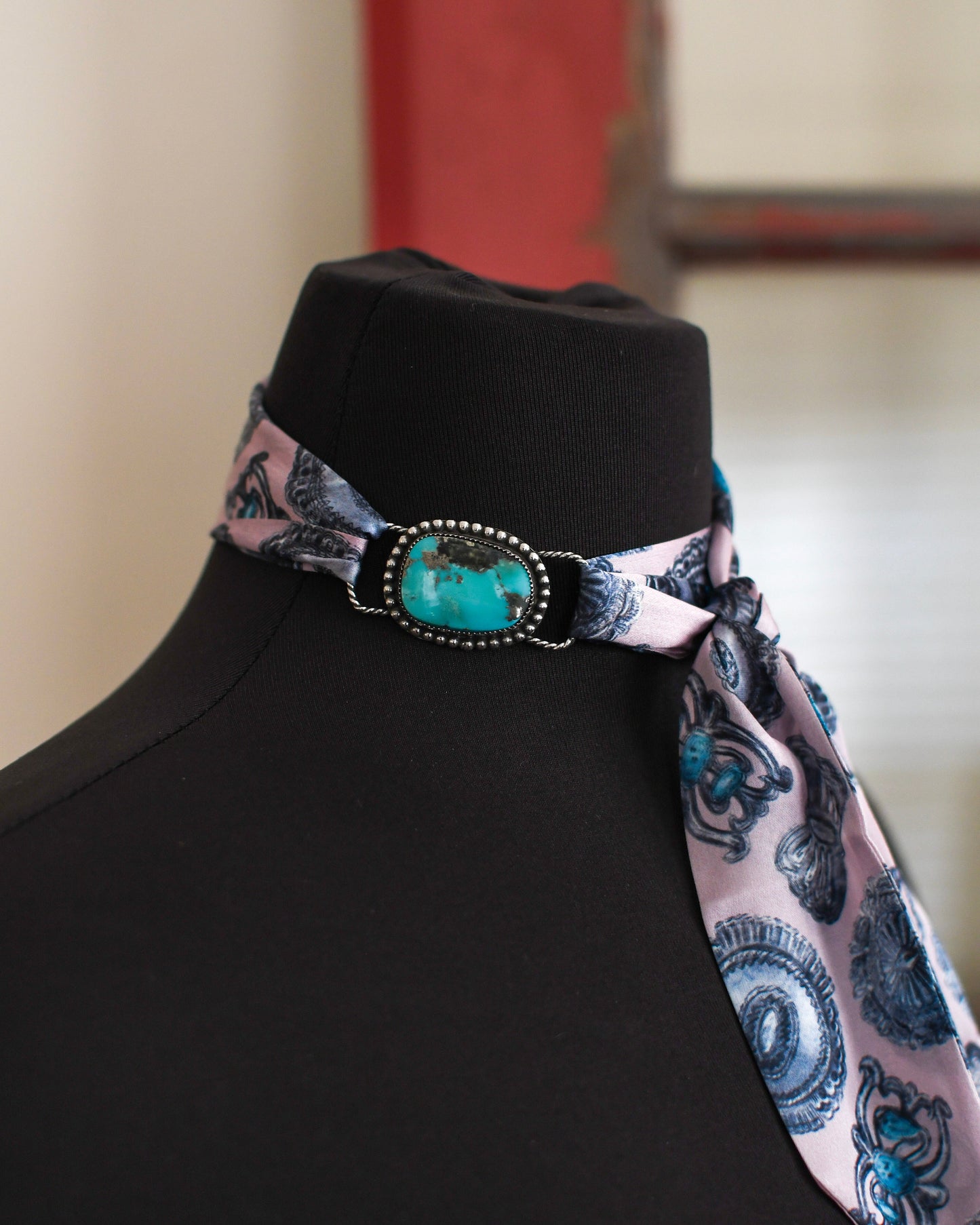 Necklace with a decorative clasp on a mannequin against a neutral background