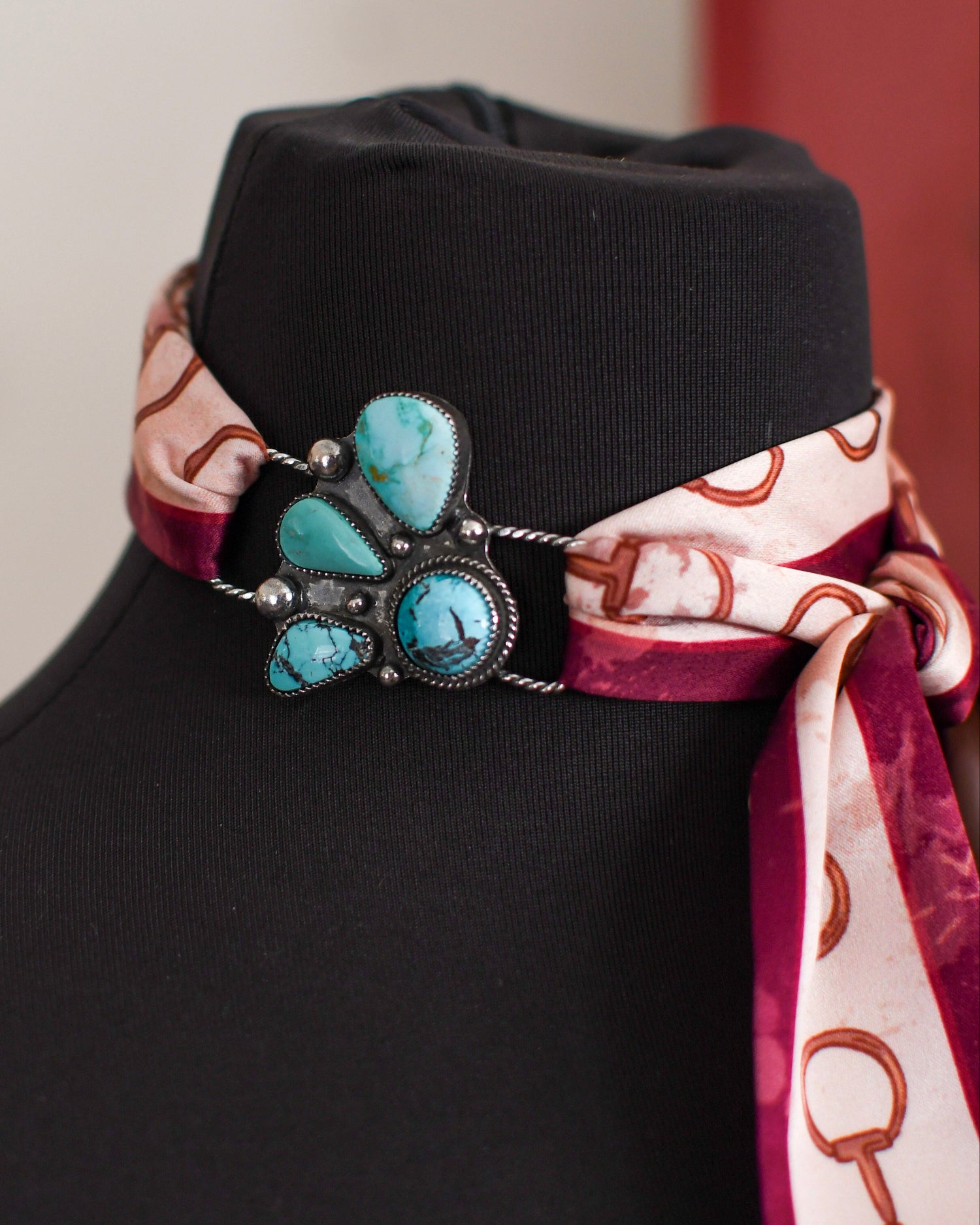 scarf with a decorative brooch and patterned scarf on a neutral background
