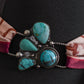 Turquoise stone twilly slide on a black mannequin with a patterned fabric strap.