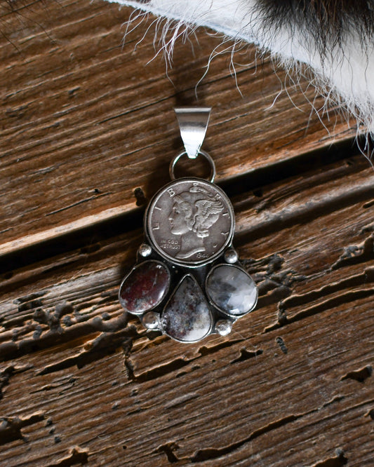 Silver pendant with embedded coins on a wooden surface