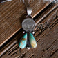 Silver pendant with turquoise stone on a wooden surface