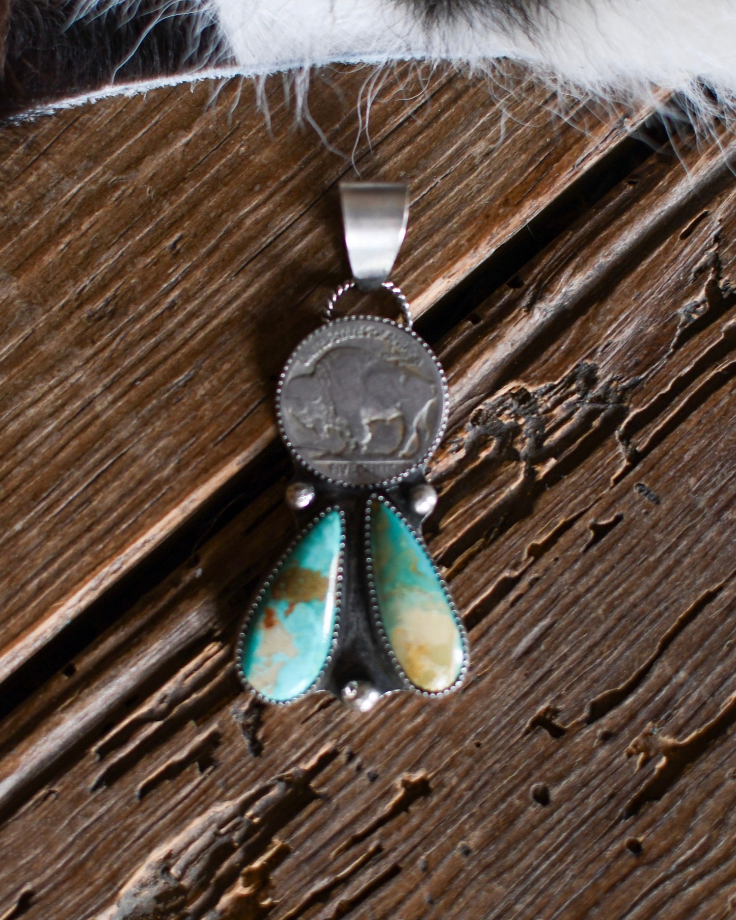 Silver pendant with turquoise stone on a wooden surface