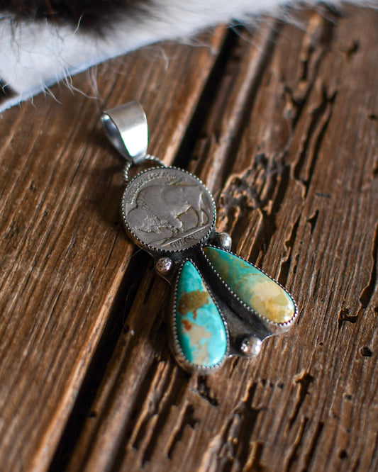 Silver pendant with turquoise stones on a wooden surface