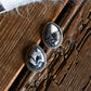 Pair of silver earrings with black and white stone on a wooden surface