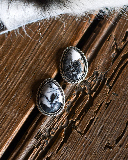 Pair of silver earrings with black and white stone on a wooden surface