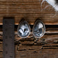 Pair of silver earrings with black and white stones on a wooden surface with a ruler for scale.
