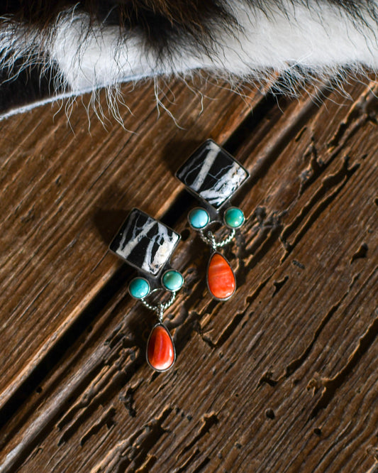 White buffalo, turquoise and orange spiny earrings on rustic wood background